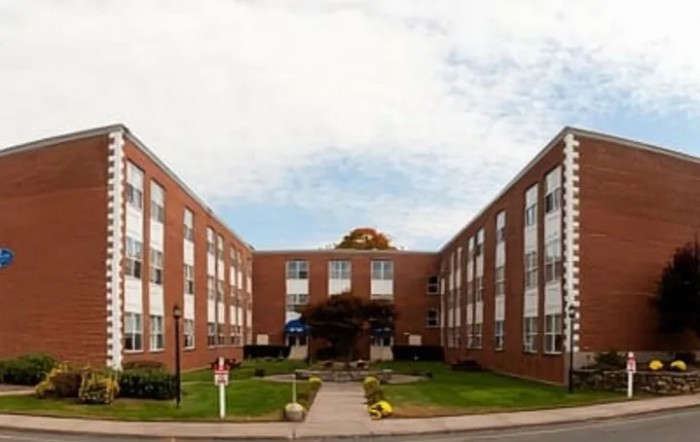 A symmetrical brick building with multiple windows and well-maintained landscaping.