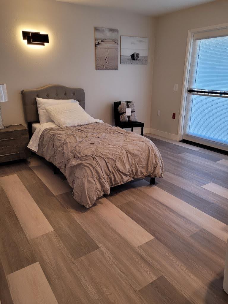 A minimalist bedroom with a single bed, wooden flooring, and modern decor.