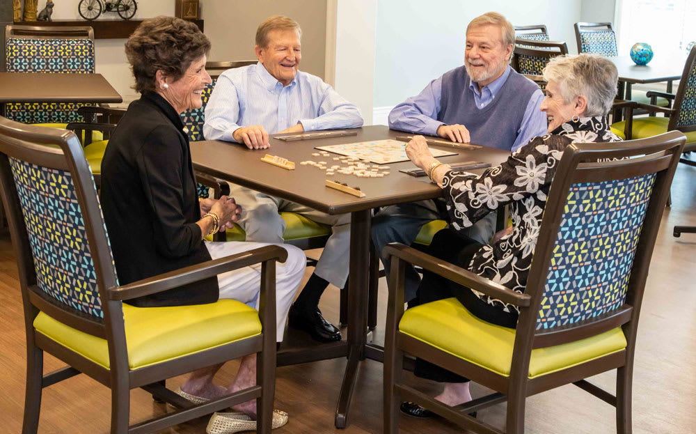 A group of seniors enjoying a game together at a table indoors.