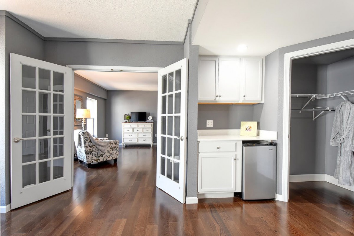 A modern interior featuring a living room and kitchenette with hardwood flooring and French doors.