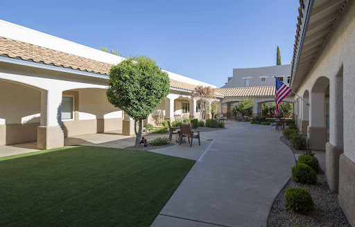A serene courtyard featuring well-maintained landscaping and an American flag.