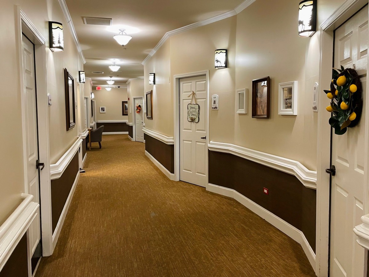 A well-lit hallway with framed pictures on the walls and a carpeted floor.