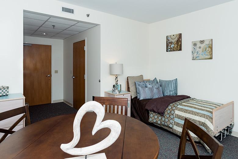 A cozy studio apartment with a neatly arranged bed and dining area.