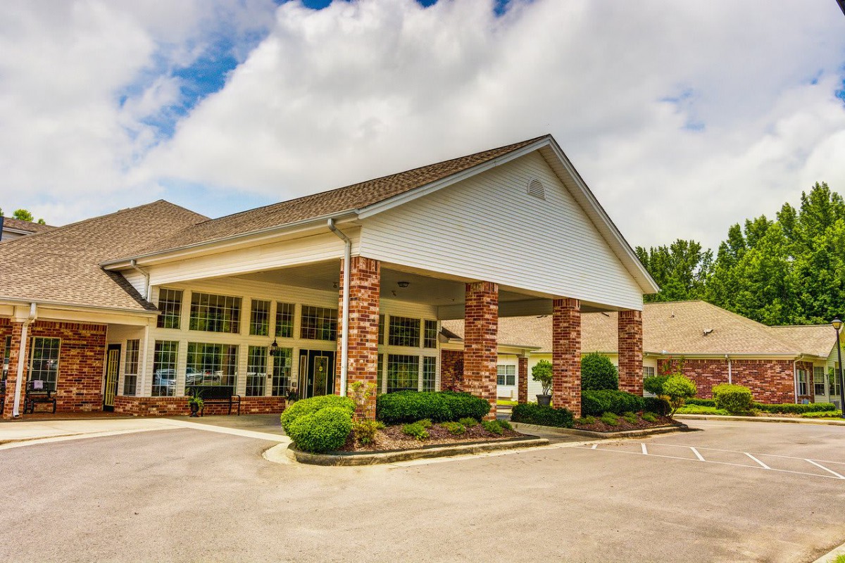 A commercial building with a covered entrance surrounded by landscaping and a driveway.