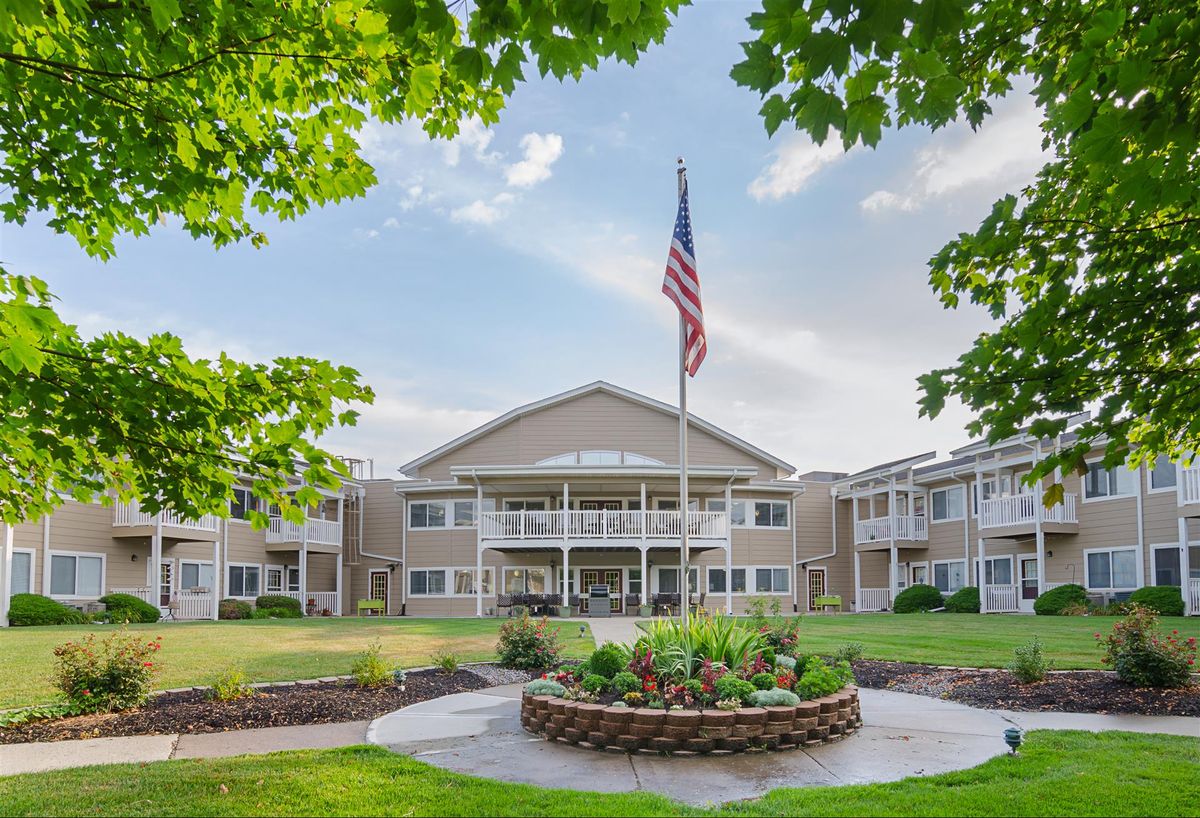 A residential building with well-maintained landscaping and an American flag in the foreground.