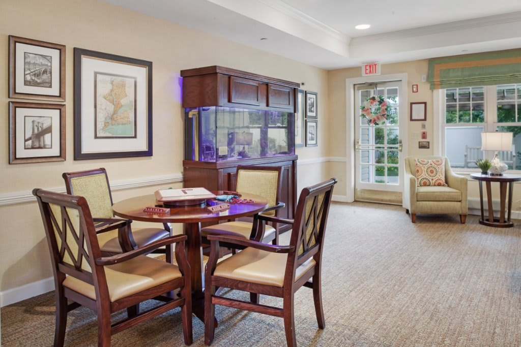 A cozy interior dining area with a round table, chairs, and a fish tank.