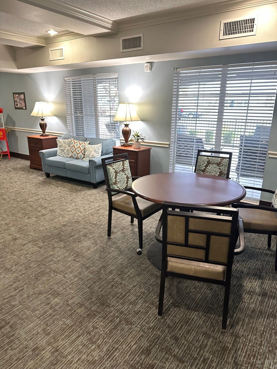 A cozy living room with a table, chairs, sofa, and lamps by the windows.