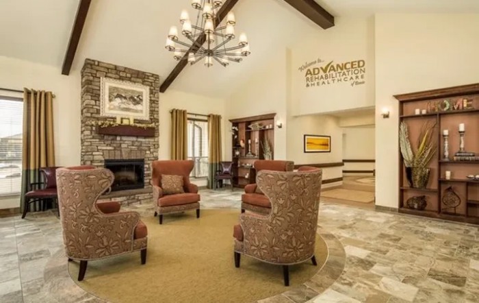 A cozy lobby interior featuring a seating area with armchairs, a fireplace, and a chandelier.