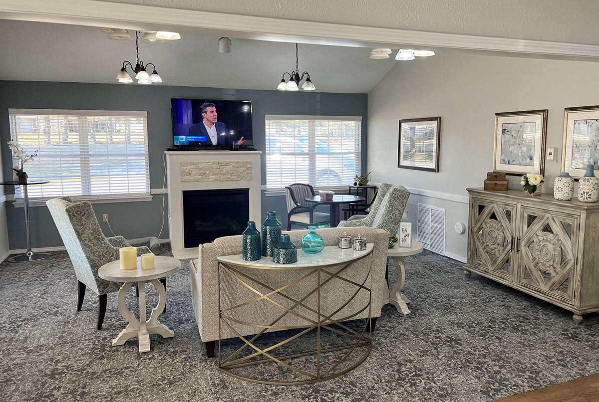 A cozy living room with a TV above the fireplace, modern furniture, and decorative elements.