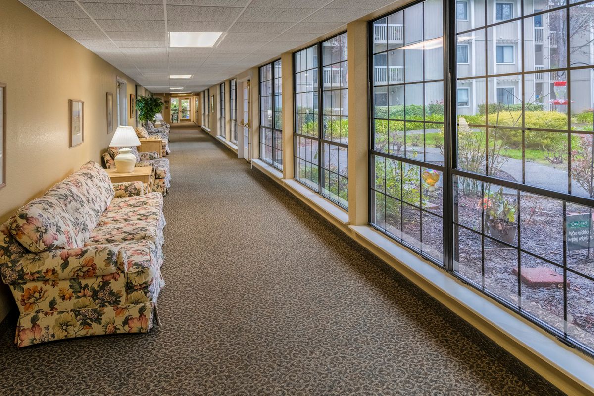 A long indoor corridor with large windows and comfortable seating.