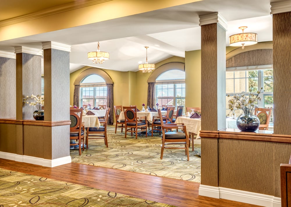 A spacious and elegantly designed dining room with tables and chairs set for guests.