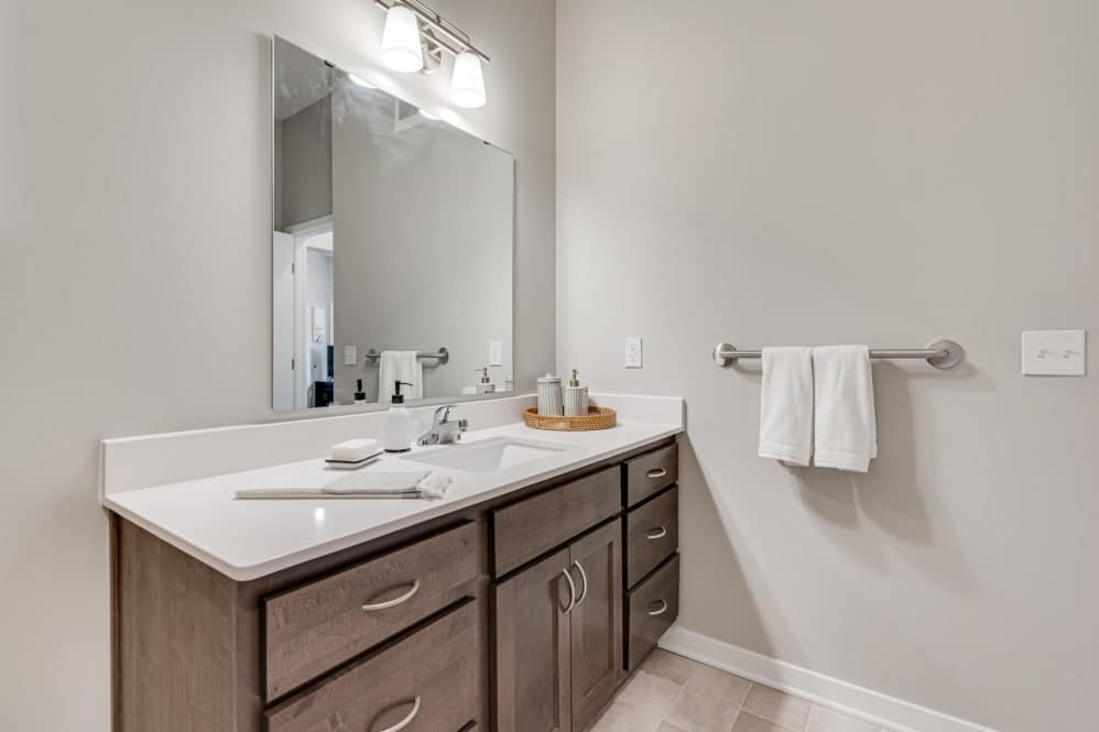 A modern bathroom with a single sink vanity and a large mirror.