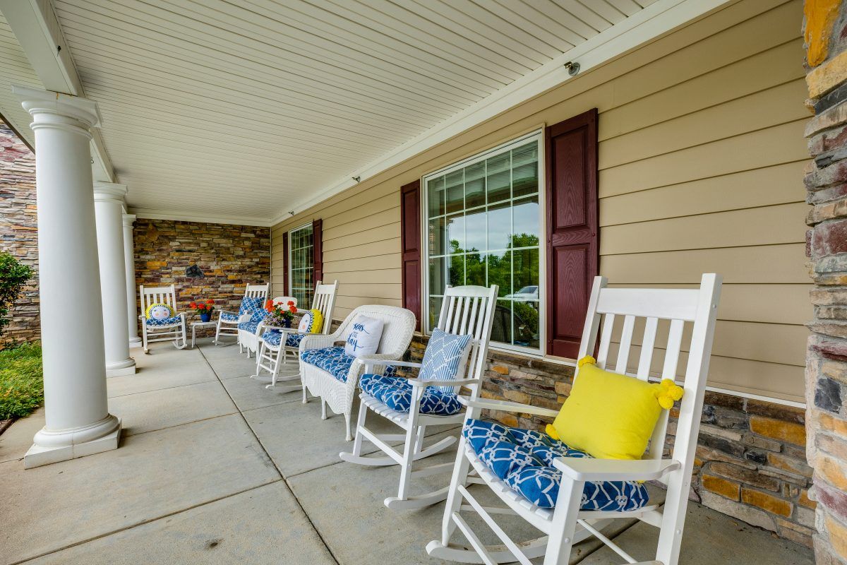A cozy porch with multiple rocking chairs adorned with colorful cushions and pillows.