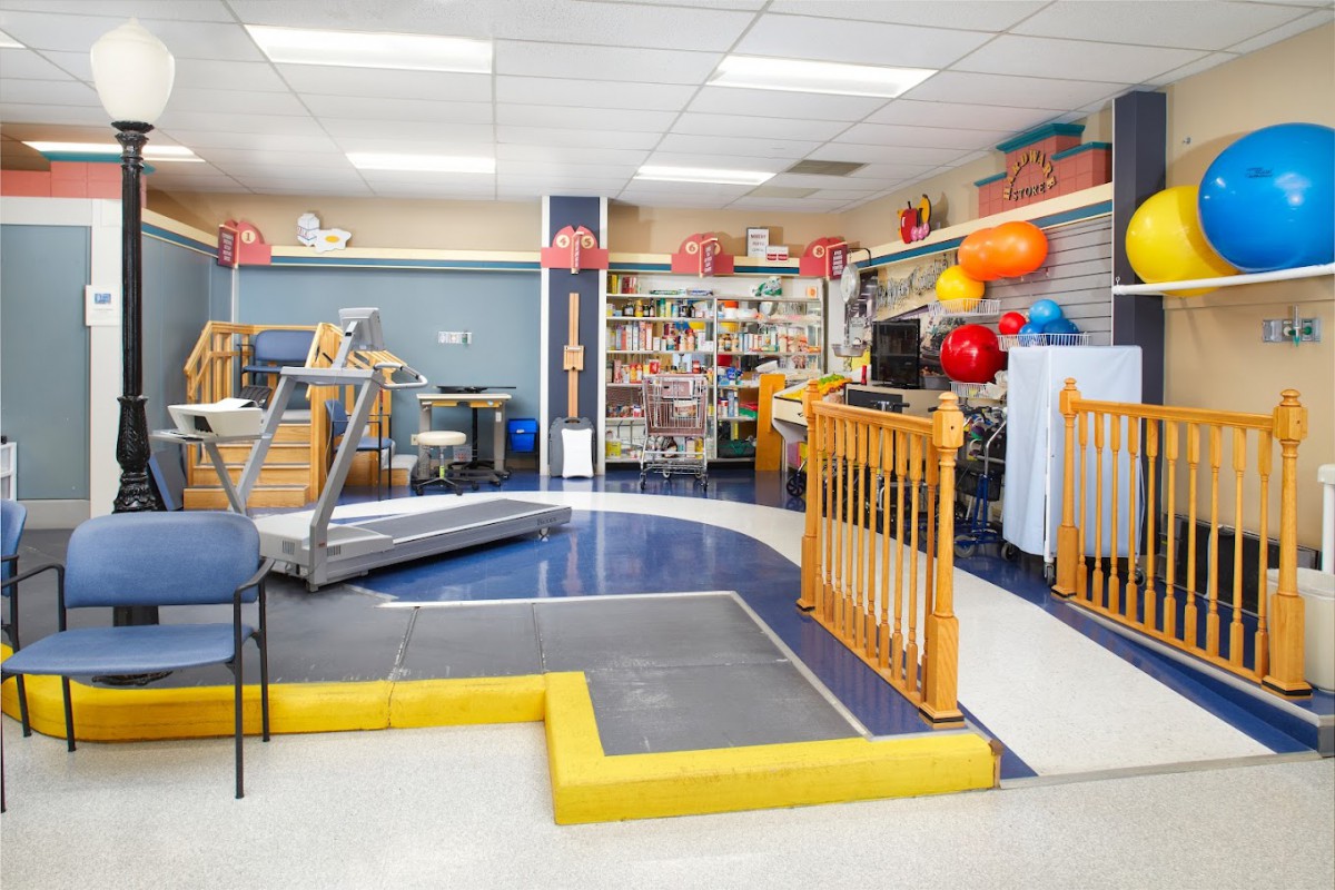 A therapy room equipped with various rehabilitation and exercise equipment, including a treadmill, therapy balls, and exercise mats.