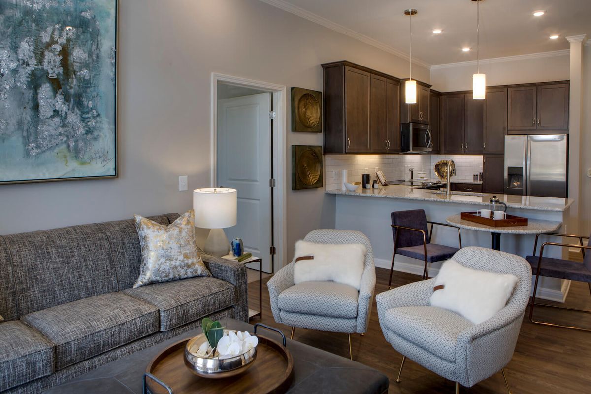 A modern living room with an open-plan kitchen, featuring stylish furniture and elegant decor.