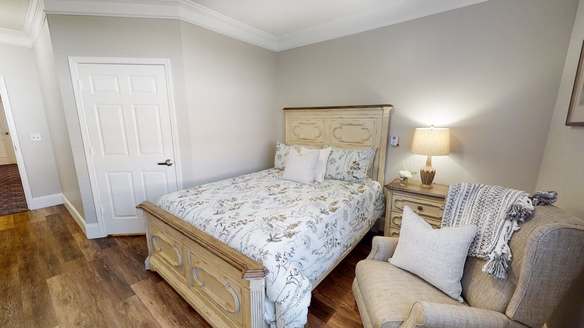 A cozy bedroom with a wooden bed, nightstand, and a comfortable chair.