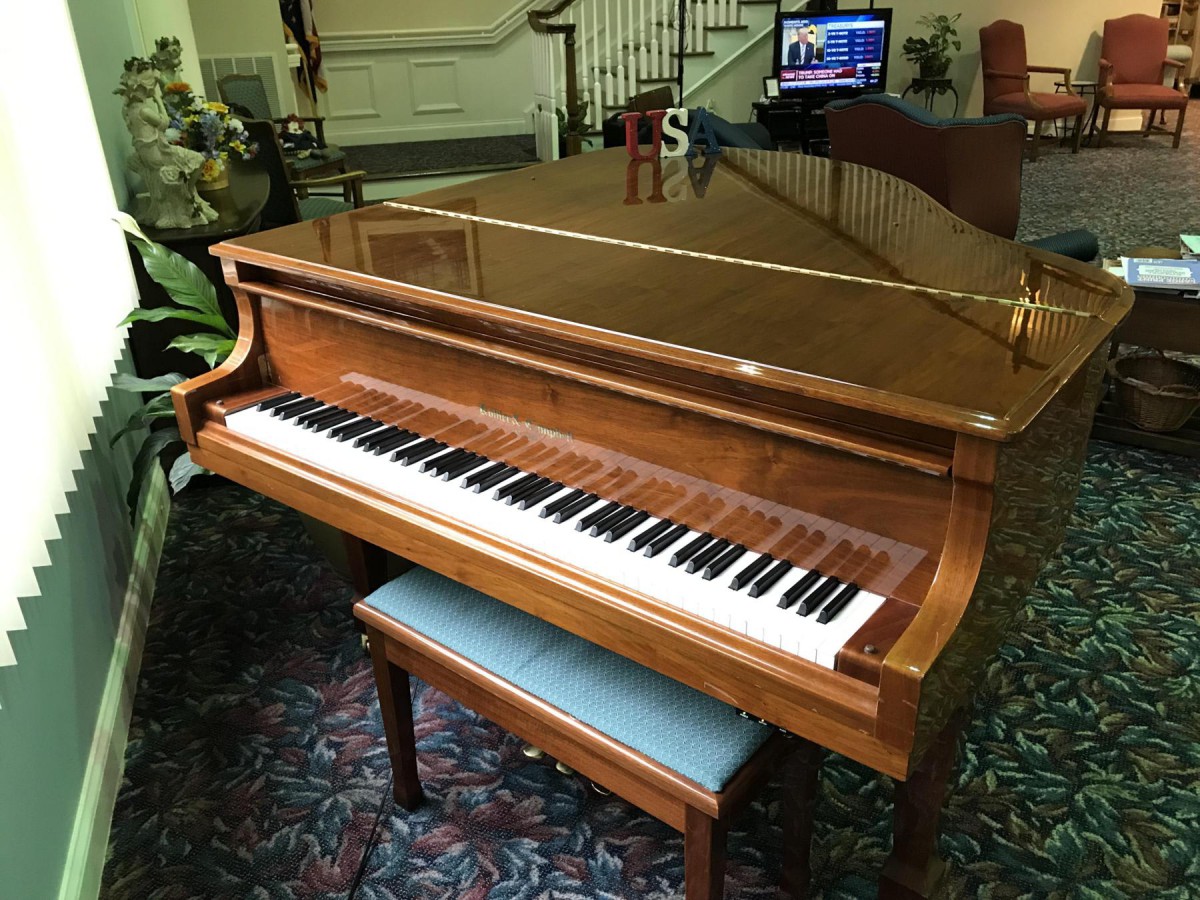 A wooden grand piano with a matching bench indoors.