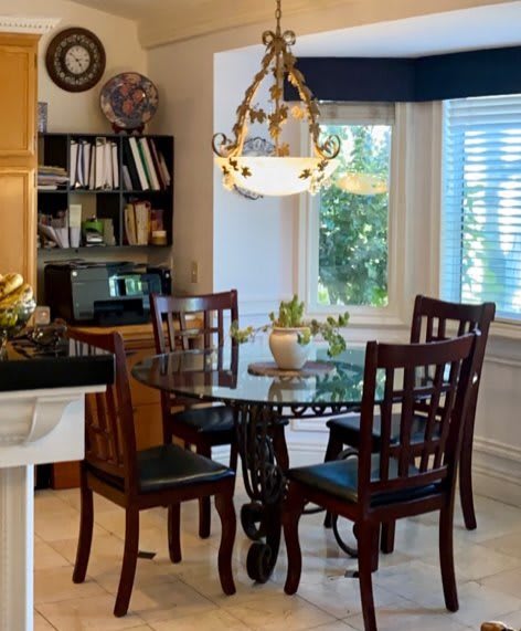 A cozy kitchen dining area with a round table, wooden chairs, and a decorative chandelier.