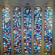 A series of colorful stained glass windows in an architectural setting.
