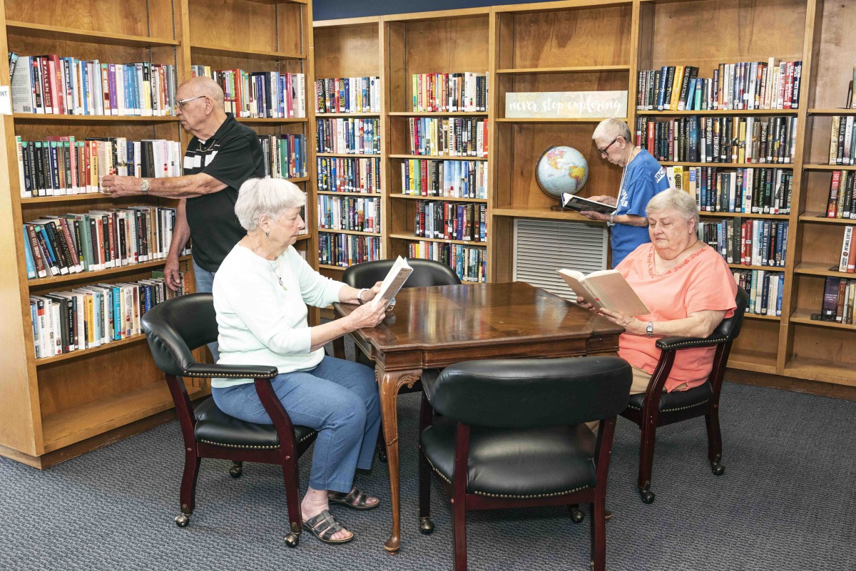 Seniors enjoying reading in a library setting.