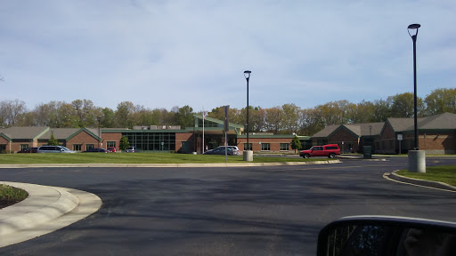 A view of a school building with a well-maintained parking lot and surrounding greenery.