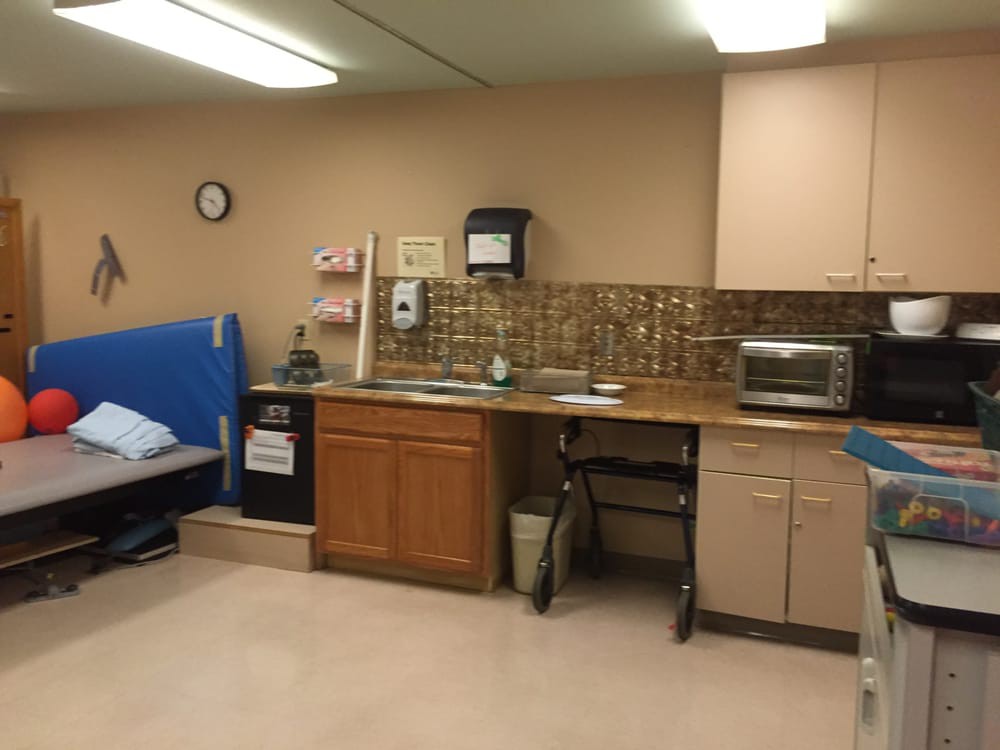 A hospital or clinic room with a bed, sink, and microwave.