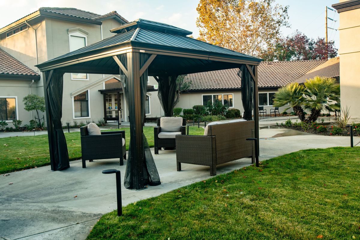 A backyard patio with a gazebo and comfortable seating area.
