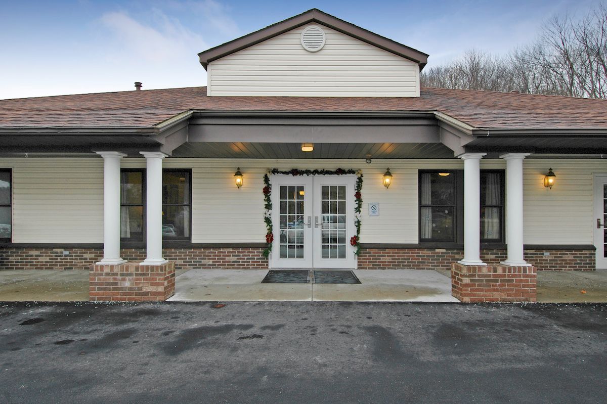 A front view of a building entrance with columns and double glass doors.