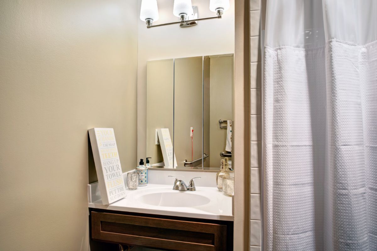 A well-lit bathroom with a mirror, sink, and decorative elements.