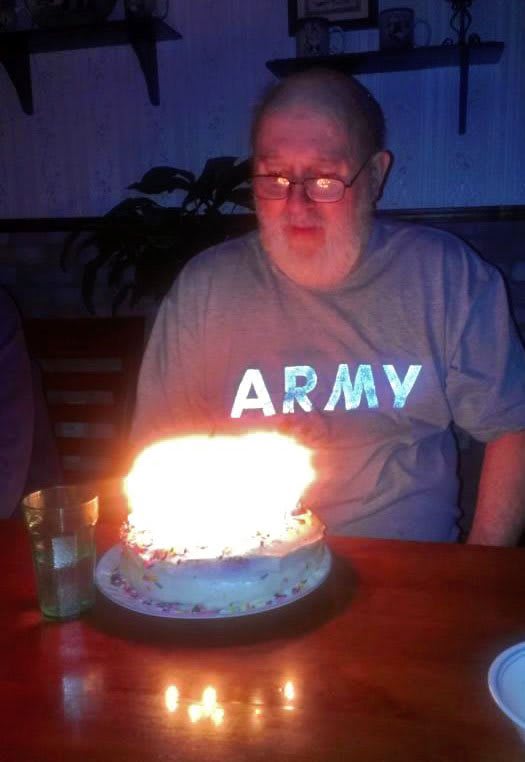 A person sitting in front of a birthday cake with lit candles.