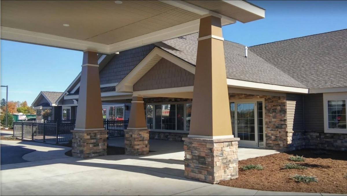 A modern building entrance with stone pillars and a peaked roof.