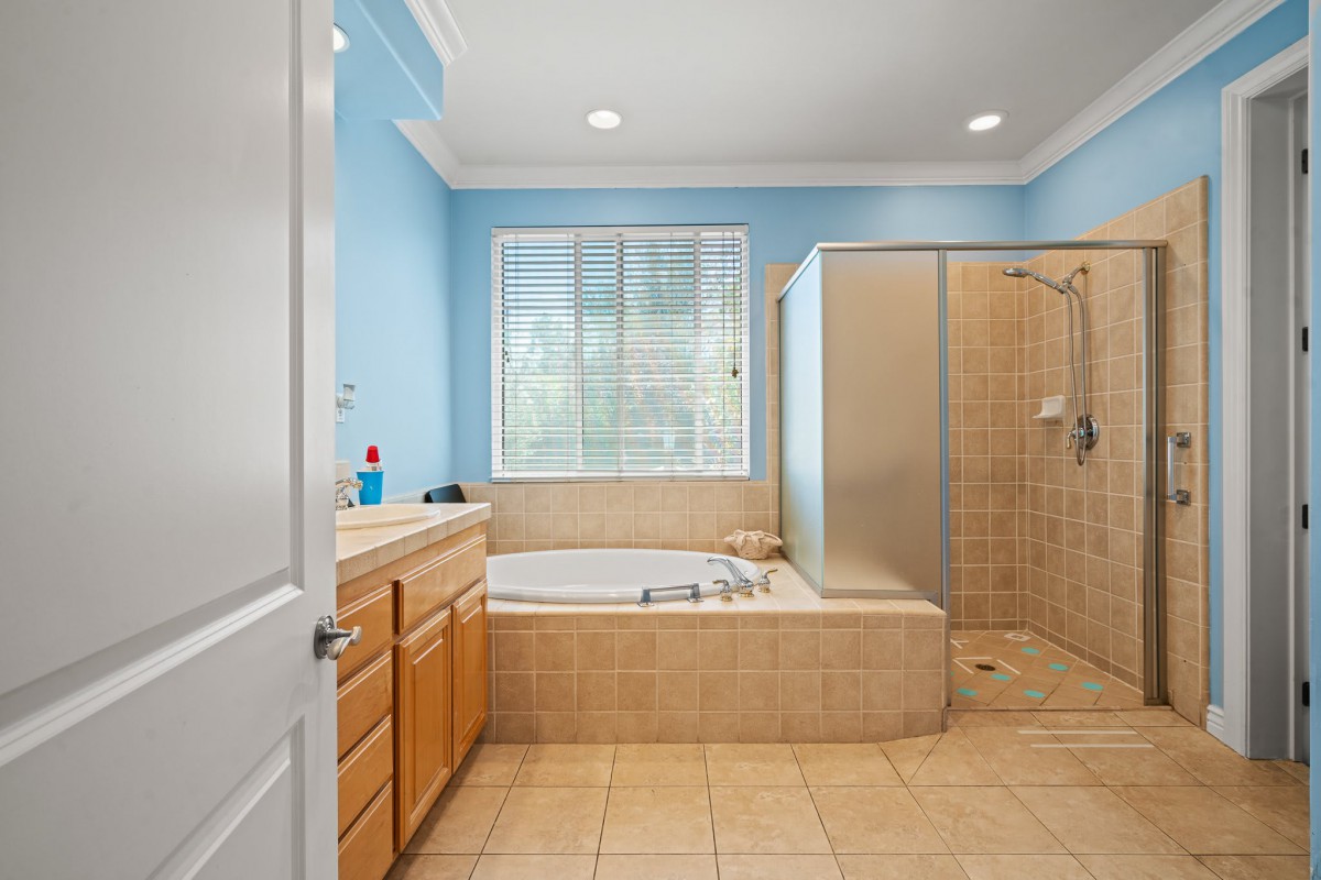 A spacious bathroom with blue walls, featuring a bathtub, shower, and wooden vanity.