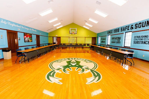 A spacious gymnasium featuring a basketball court and vibrant walls, designed for community events and sports activities.