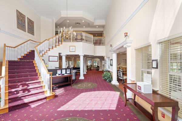 Spacious hotel lobby with a grand staircase and chandelier.