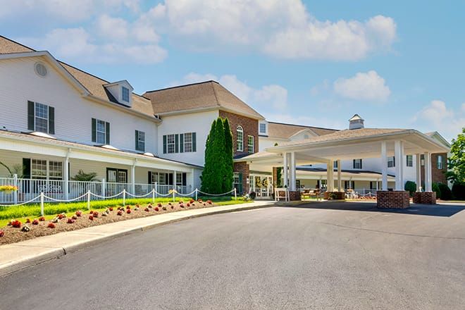 A large residential building with a driveway and well-maintained landscaping under a cloudy sky.