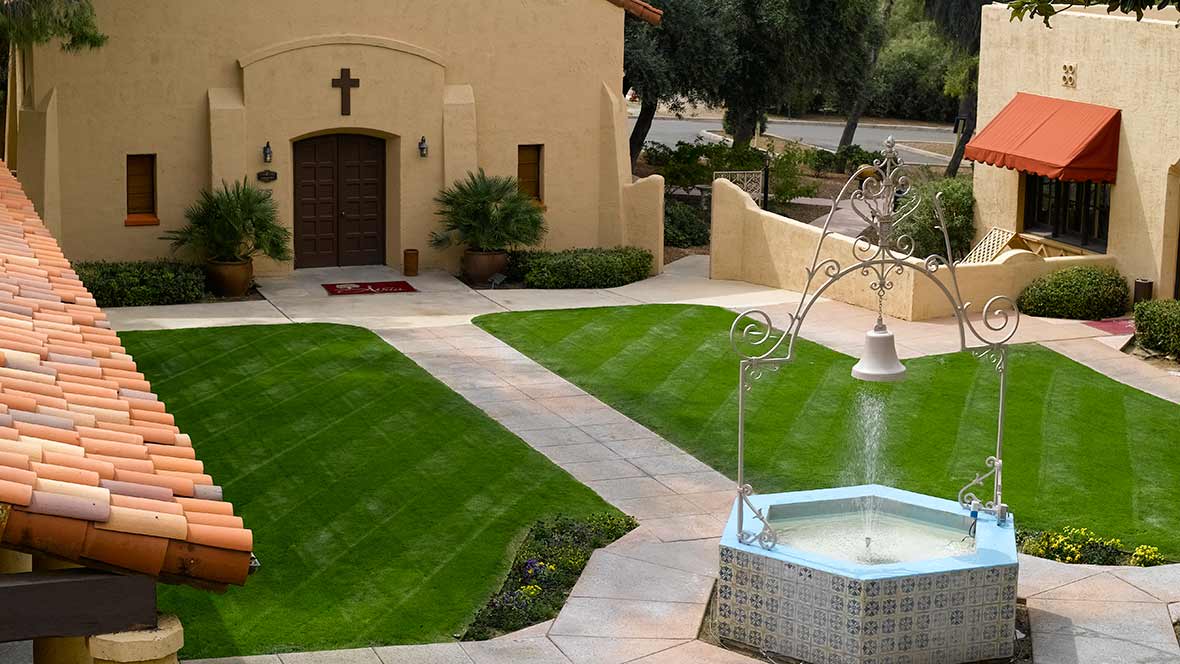 A serene church garden featuring a fountain and well-maintained pathways.