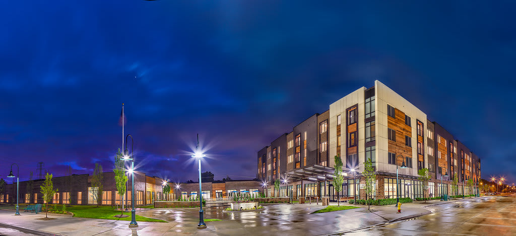 A modern building illuminated at night with reflective wet pavement.