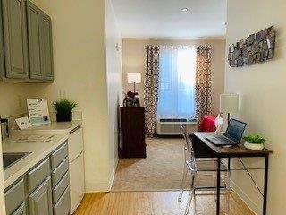 A cozy studio apartment with a simple desk setup and natural light.