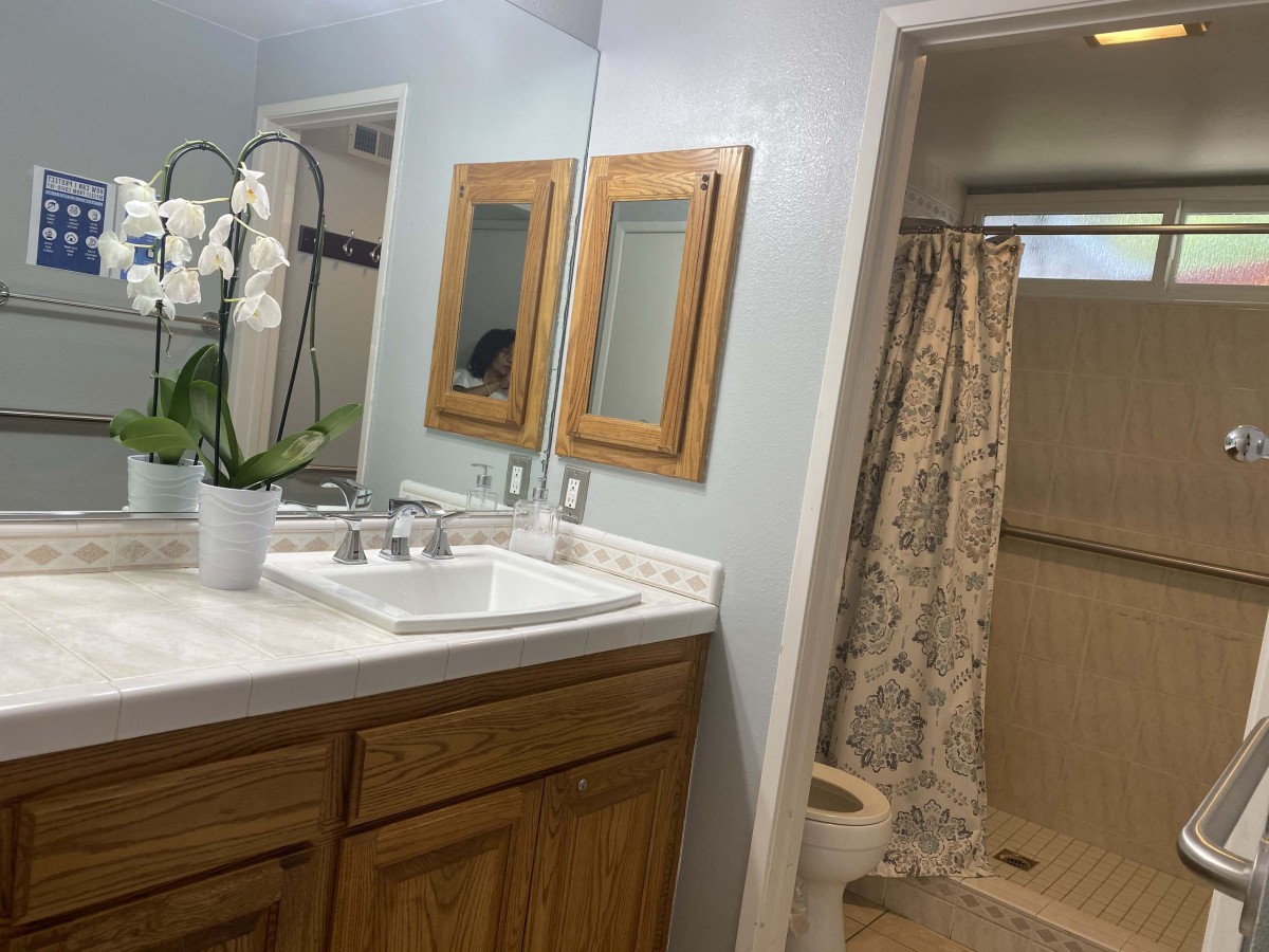 A clean and modern bathroom with a wooden cabinet, dual mirrors, and a floral shower curtain.
