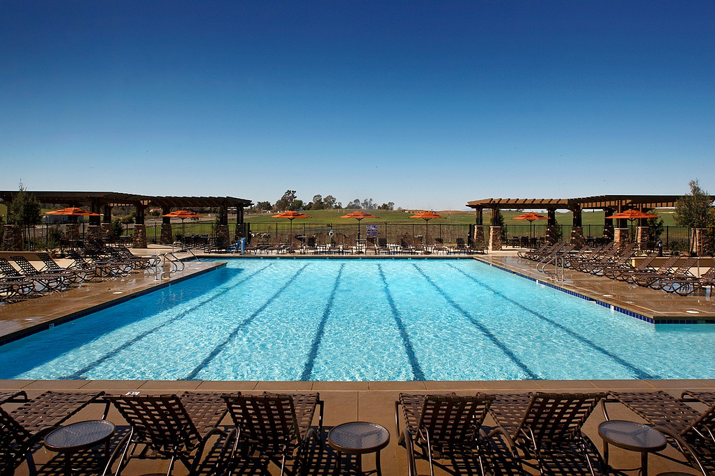 A serene outdoor swimming pool with lounge chairs under a clear blue sky.