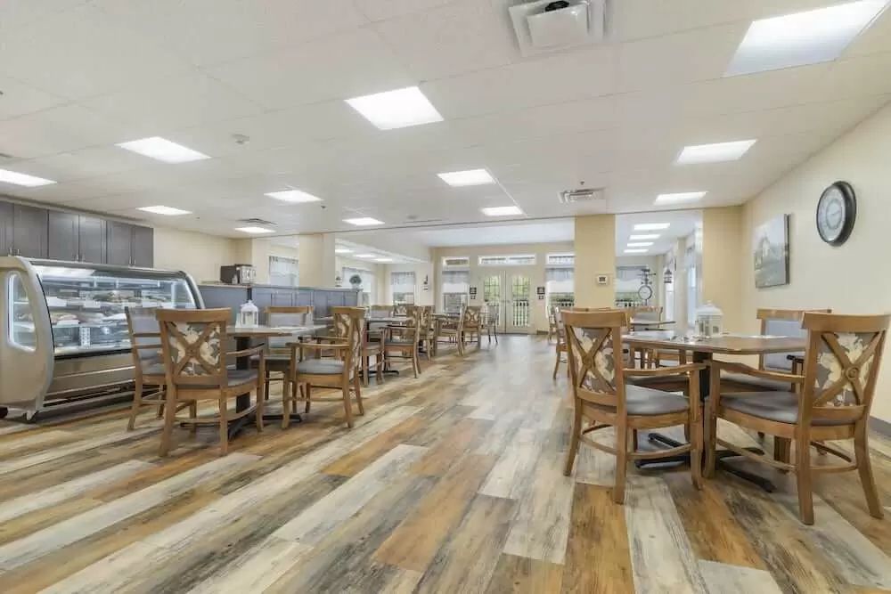 An empty restaurant dining area with wooden flooring and seating.