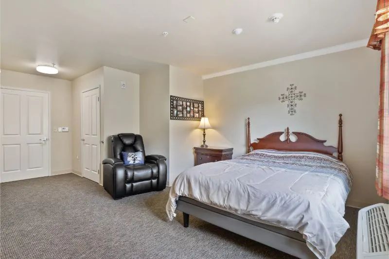 A cozy bedroom with a large bed and armchair.
