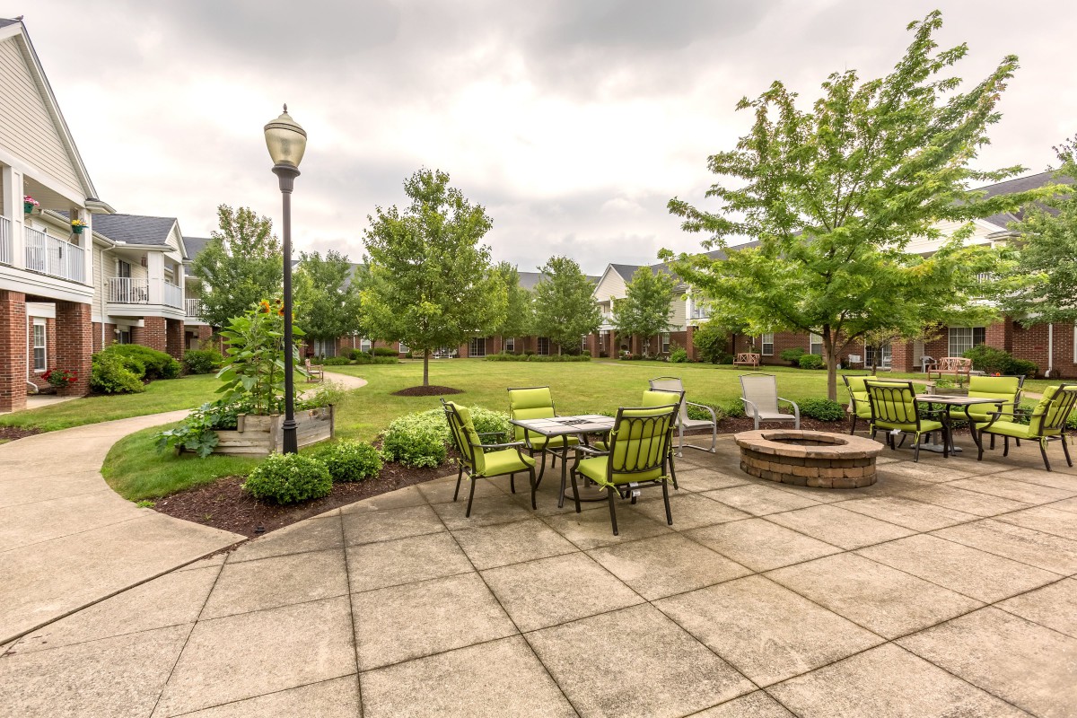 A peaceful patio with outdoor seating overlooking a green lawn and surrounded by trees.