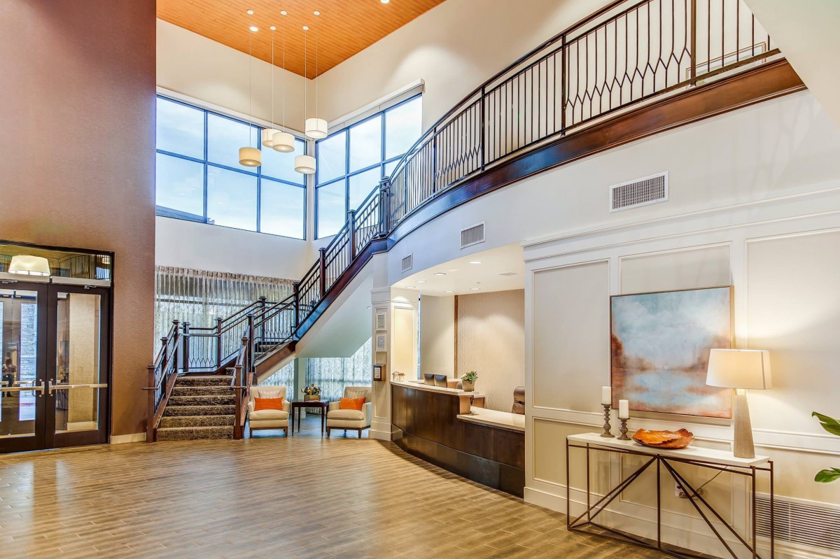 A modern lobby with a grand staircase and reception area.