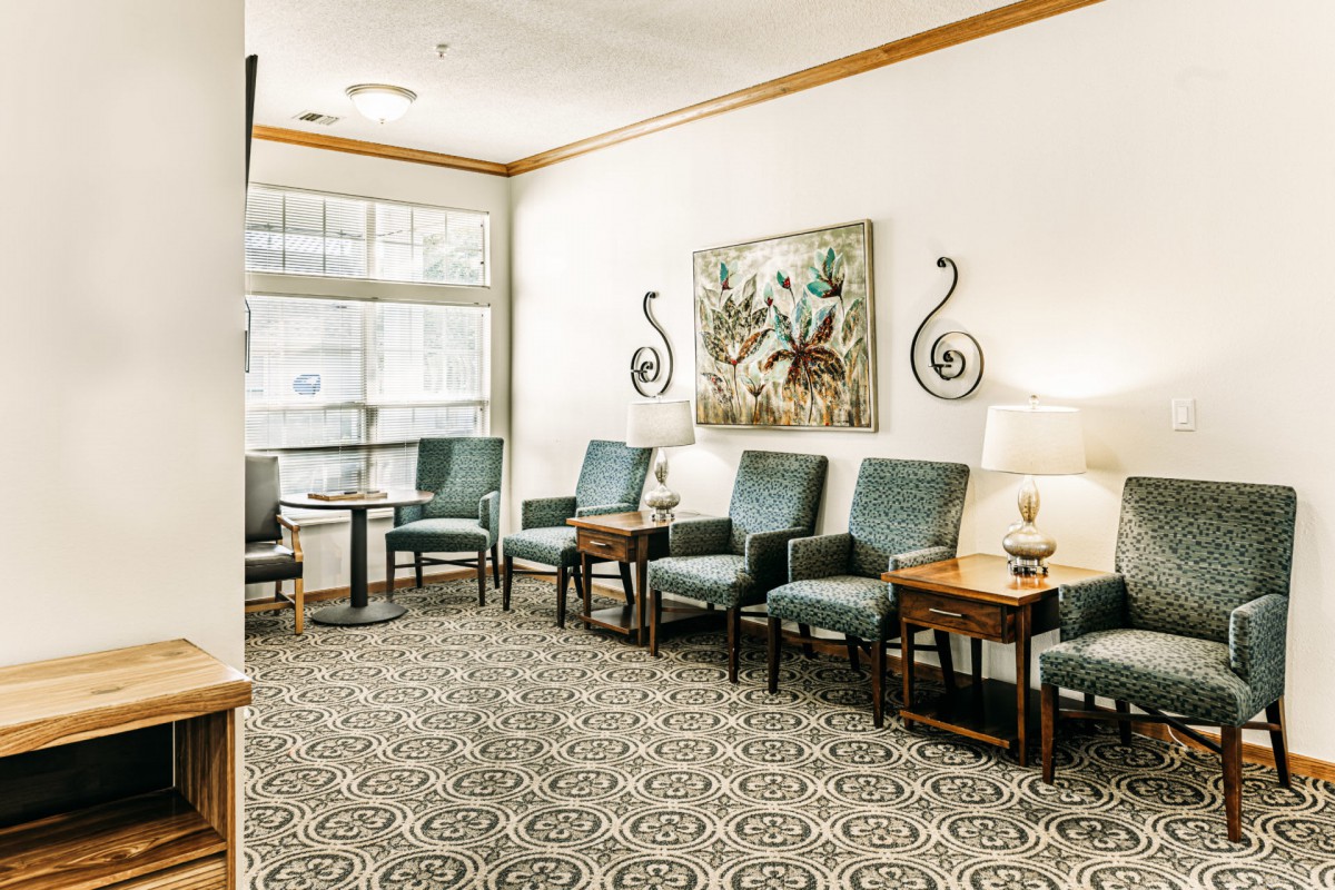 A cozy waiting room with comfortable chairs, small tables, and decorative artwork on the wall.