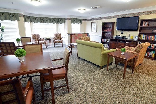 A cozy living room with chairs, tables, a sofa, and a television.