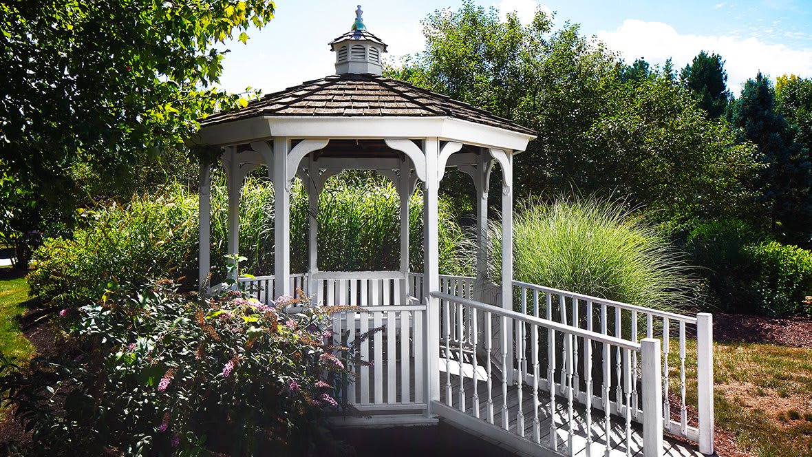 A charming wooden gazebo in a lush garden setting.