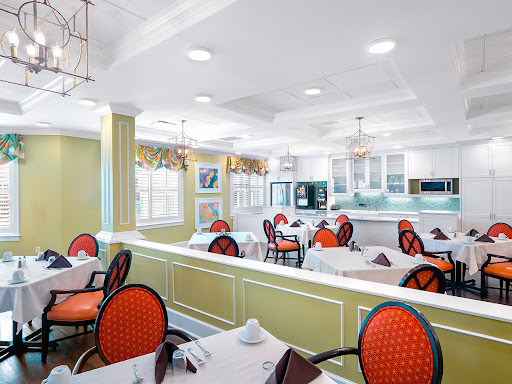 A stylish and modern dining area featuring vibrant red chairs and a bright, open kitchen space.