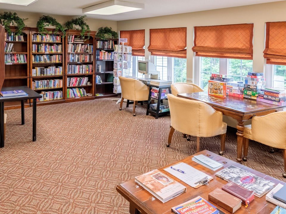 A cozy library room with bookshelves, tables, and chairs for reading.