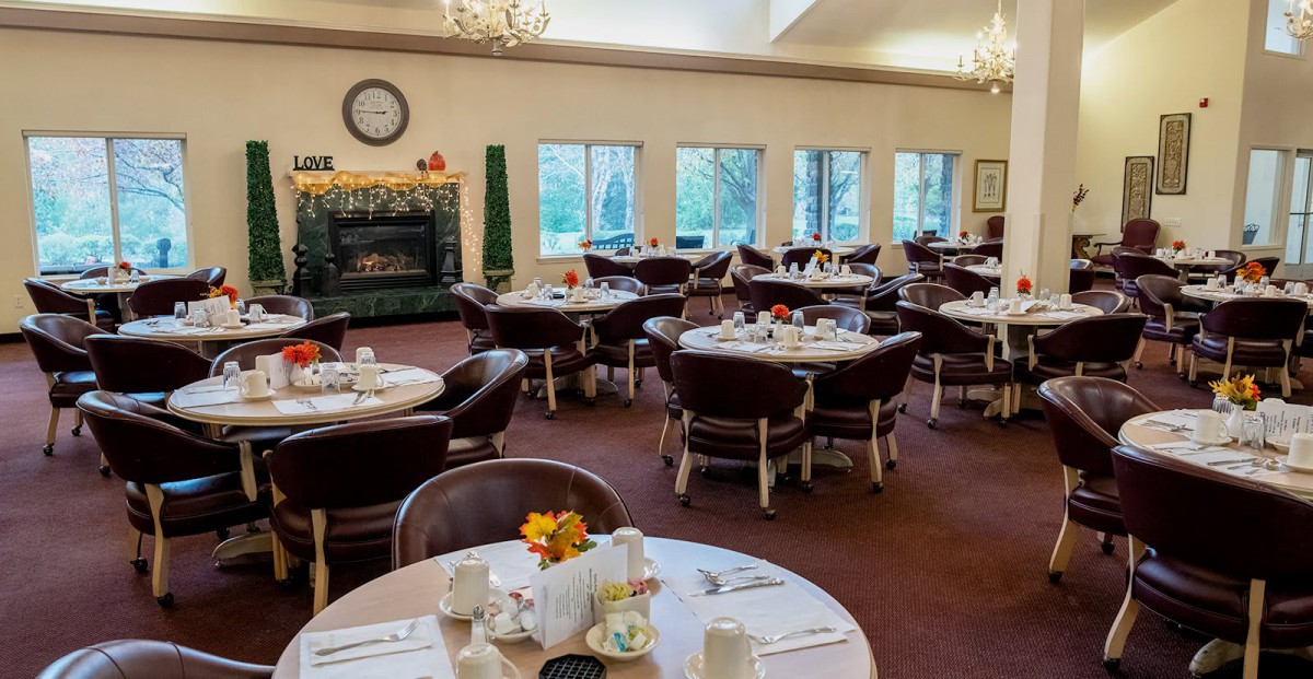 An elegant dining room setup with circular tables and leather chairs, ready for guests.